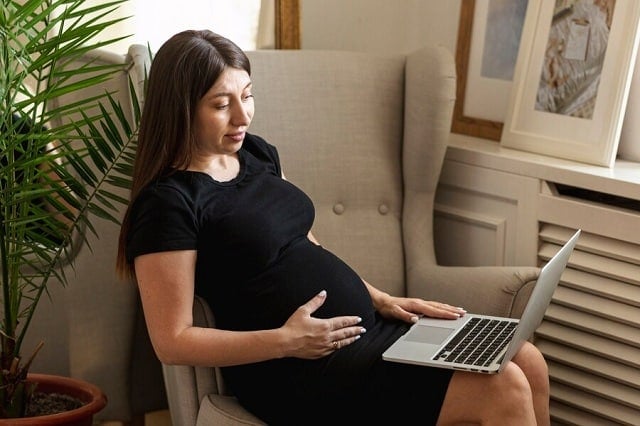 femme enceinte tenant son ordinateur portable