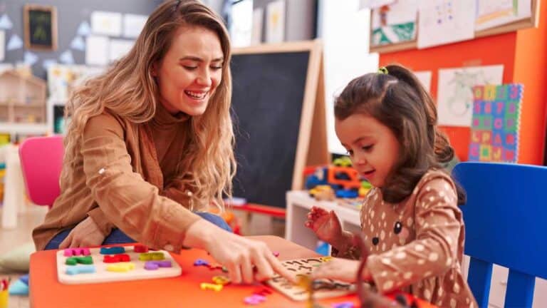 Un adulte et un enfant sont assis à une table et participent à une activité éducative ludique avec des pièces de puzzle colorées dans une pièce bien éclairée.